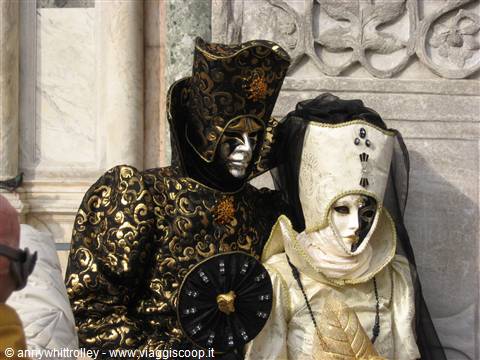 Masks in black and gold brocade costumes at Venice Carnival