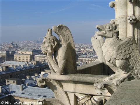 Thoughtful stone gargoyle beside an eagle atop Notre-Dame over Paris rooftops