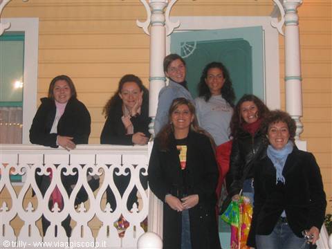 Group of smiling young women on yellow wooden porch with white railing
