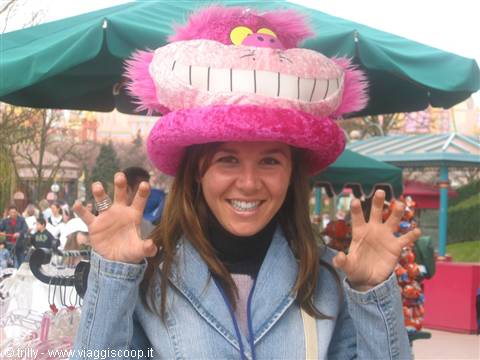 Smiling girl wearing a pink fuzzy Cheshire Cat hat under green umbrellas
