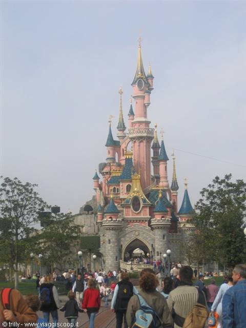 Pink and blue Disneyland Paris castle with tourists strolling under gray sky