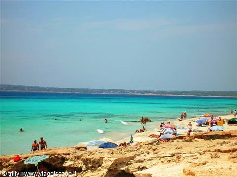 Golden rocks, beach umbrellas and swimmers in turquoise water