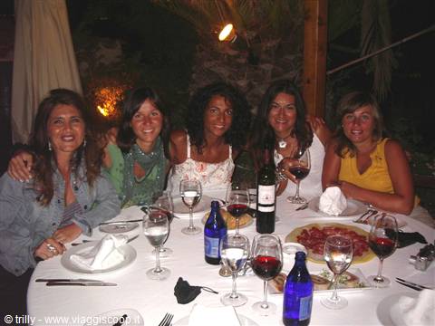 Five smiling friends toast with wine glasses around a set dinner table
