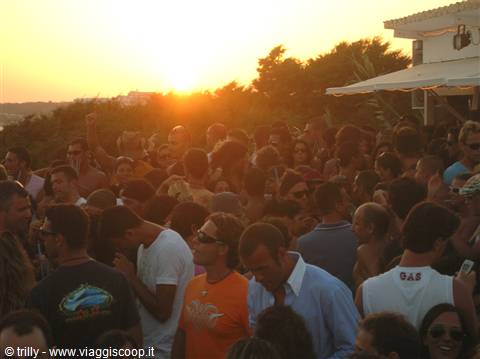 Crowd partying at sunset on a packed terrace with trees and awning
