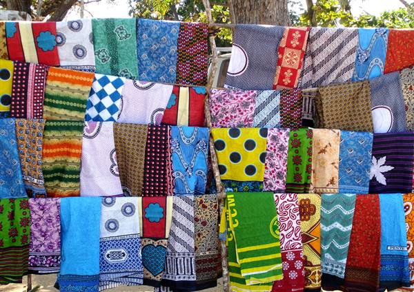 Colorful fabrics hanging on wooden poles, African market stall
