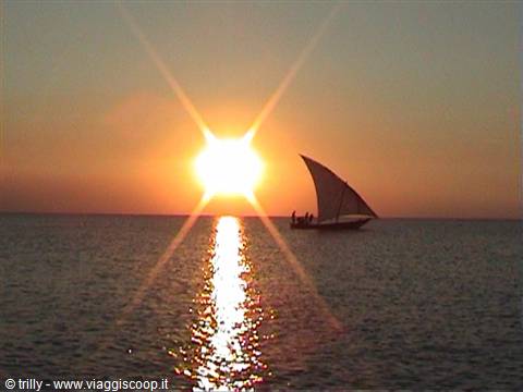 Sailboat dhow with people on the sea, golden reflection of the low sun