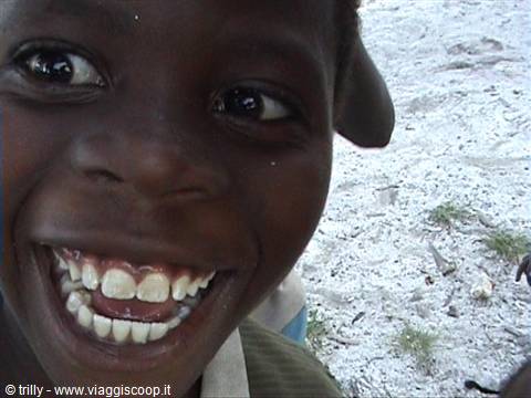 Smiling boy close-up on white sand in daylight