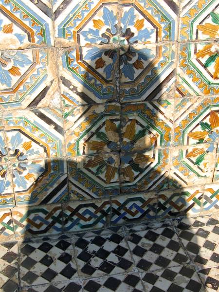 Woman's shadow on decorated majolica tiles in Seville, bright sunlight