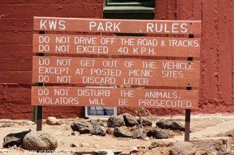 Wooden sign with KWS park rules, against a red wall
