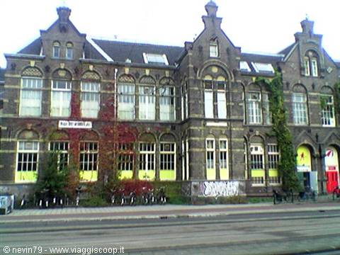 Brick facade of an old Amsterdam building, bicycles parked beneath the windows