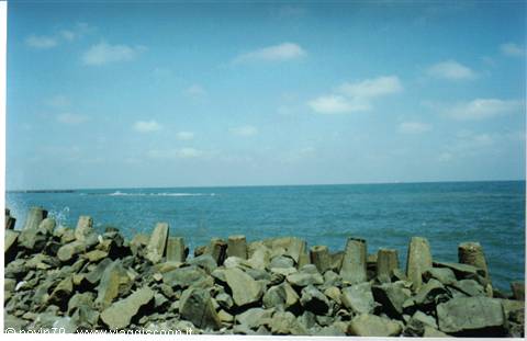 Concrete blocks protecting the coast, blue sea and cloudy sky