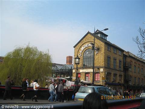 People walk past the brick Camden Lock Market building by the canal