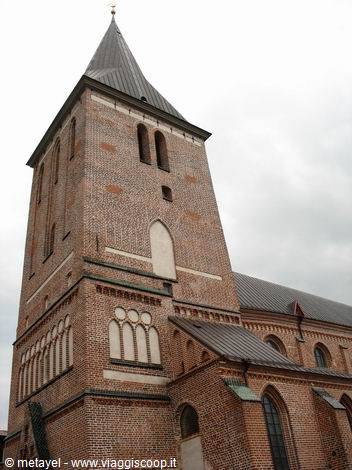 Red brick tower of Odense Cathedral against a grey cloudy sky