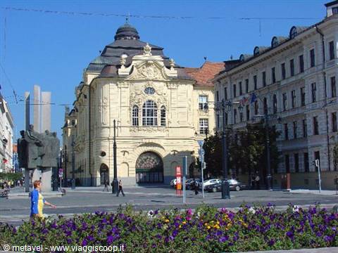 Slovak National Theatre in Bratislava, yellow facade in sunlight, flowers in front