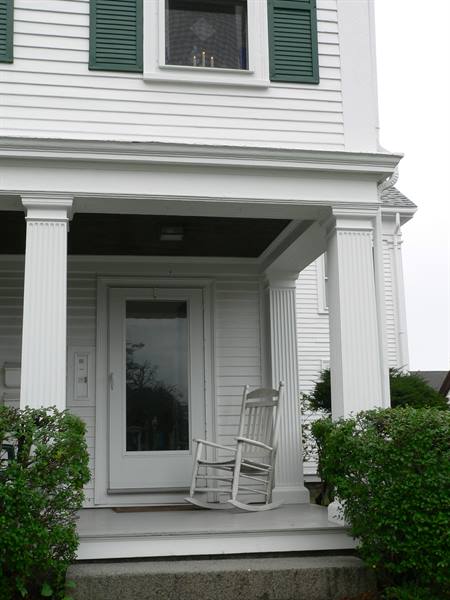 White rocking chair on the porch of a wooden house