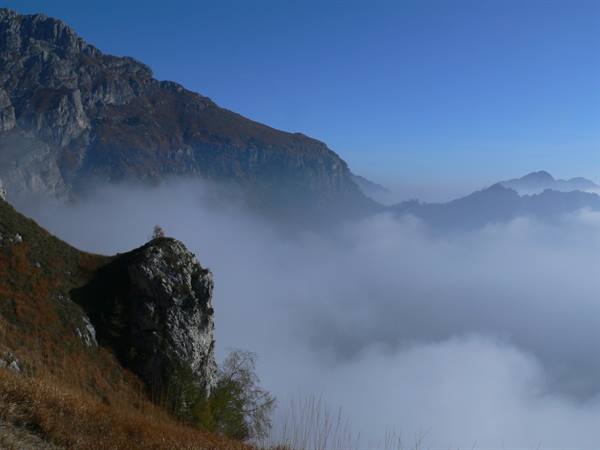 Rocky outcrop above fog, autumn mountains under clear blue sky