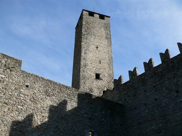 Stone battlemented tower of Castelgrande, Bellinzona, walls against blue sky