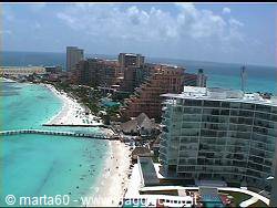 Sandy beach lined with hotels and umbrellas on turquoise Caribbean water, Cancún