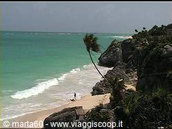 Tulum beach: leaning palm over rocky cliff, person walking on white sand