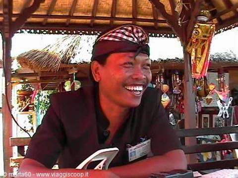 Smiling Balinese man wearing an udeng under a wooden thatched pavilion
