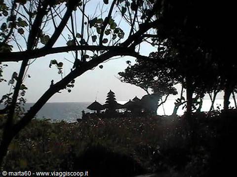 Balinese temple Tanah Lot backlit through trees by the sea