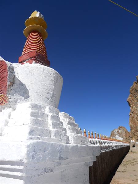 White stupa with red and golden spire under clear blue sky