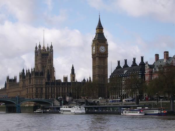 Big Ben and Westminster Palace seen across the Thames, boats moored by the bridge