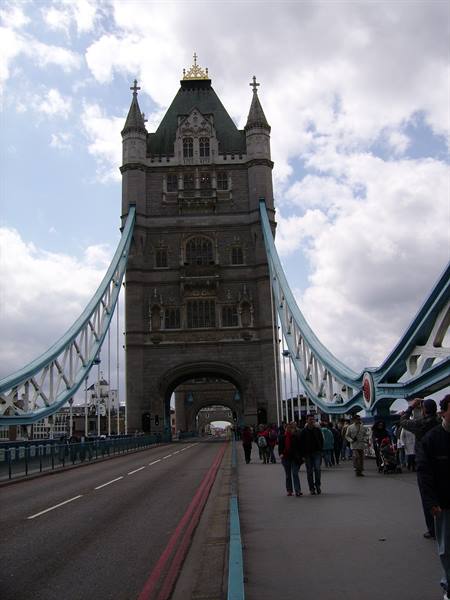 Tourists walk along Tower Bridge walkway beneath the stone tower