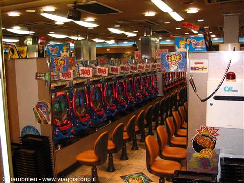 Japanese pachinko parlor with rows of bright machines and empty orange stools