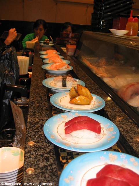 Sushi plates moving on conveyor belt at restaurant, tuna and salmon