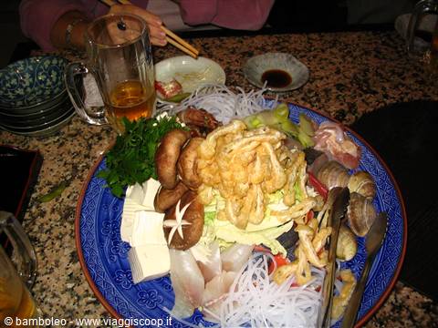 Blue plate with shiitake mushrooms, tofu, noodles and tempura on granite table