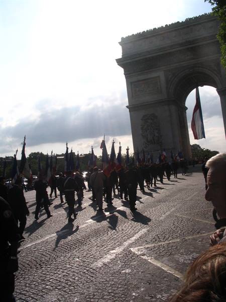 Flag parade beneath the Arc de Triomphe in Paris, backlit