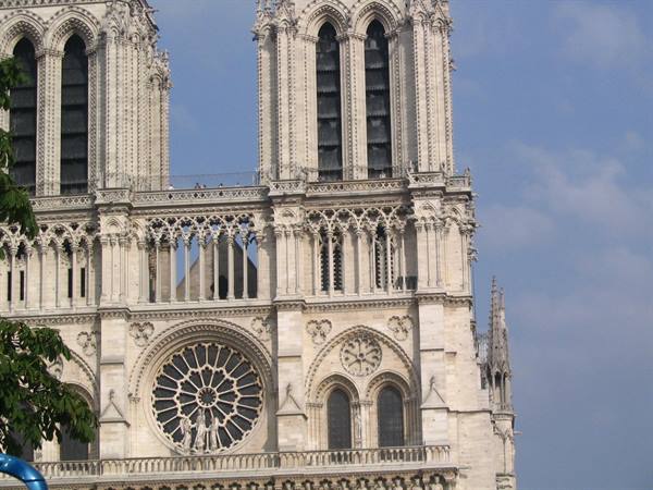 Gothic facade of Notre-Dame in Paris, stone rose window under blue sky