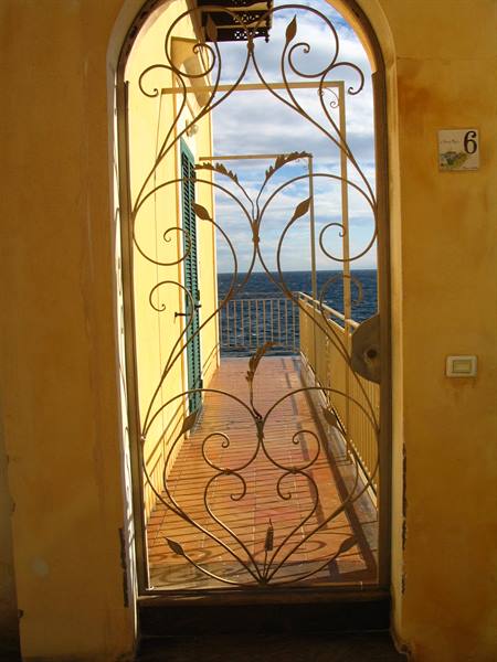 Ornate wrought iron gate opening onto a terrace overlooking the sea