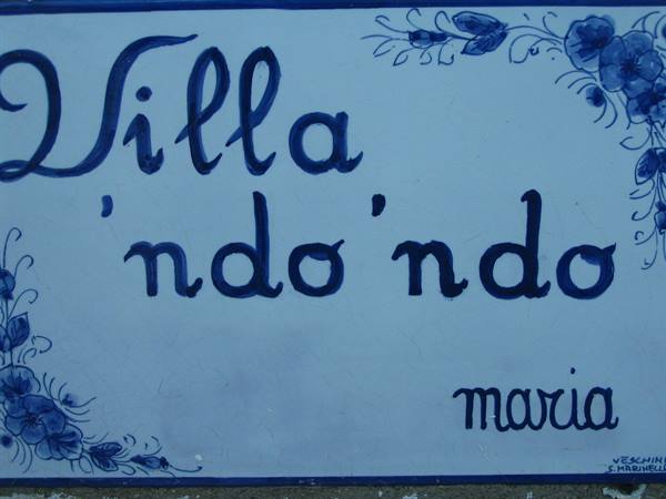 Blue ceramic tile sign reading Villa 'ndo'ndo Maria with painted flowers