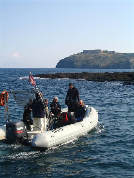 Divers on a Yamaha inflatable boat near volcanic rocks at Ustica