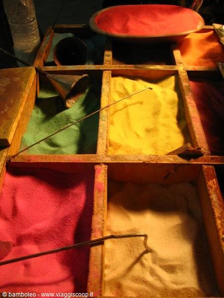 Wooden box filled with colored sand and metal funnels for sand art