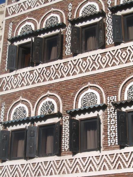 Brick facade with arched windows, white latticework and black shutters, Sana'a
