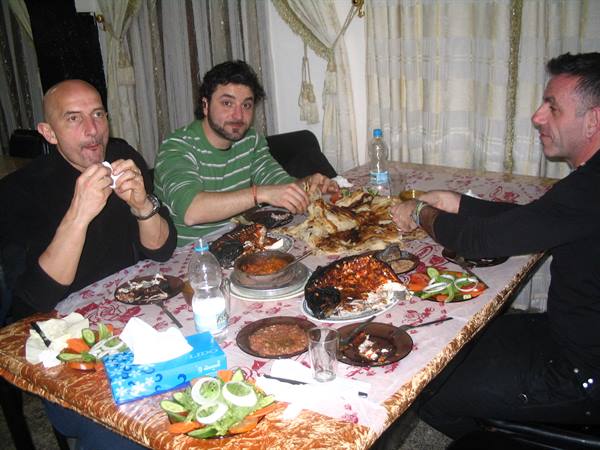 Three friends eating fish and salad around a table indoors