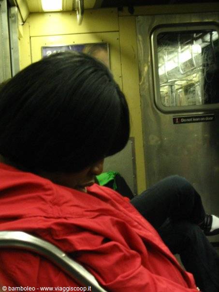 Woman in red jacket asleep on the metal seats of the subway