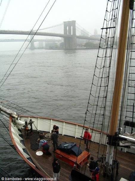 Crew on wooden sailing ship deck, Brooklyn Bridge in the fog