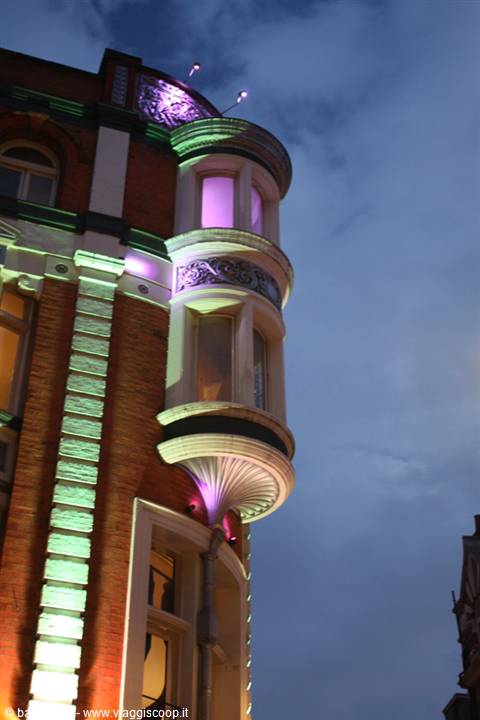 Brick building with rounded bay windows lit by green and purple lights