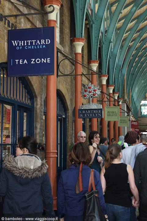 Shoppers under Covent Garden's green arches, past Whittard and Crabtree & Evelyn signs