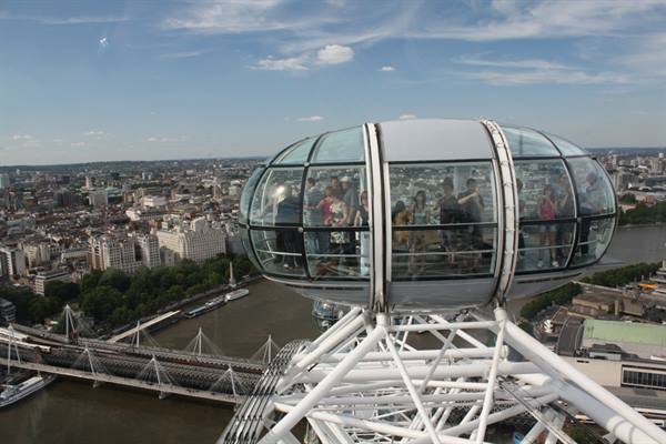 Glass capsule of the London Eye with passengers above the Thames and bridges