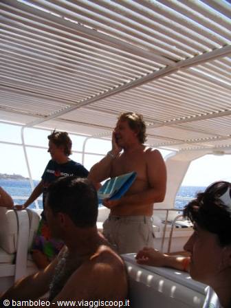 Shirtless tourists under a boat canopy, one man talking on the phone