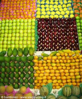 Market stall with apples, mangoes and melons arranged in colorful rows