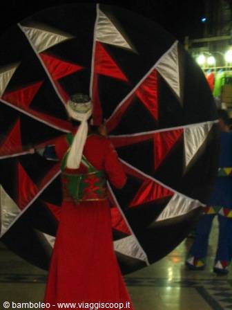 Whirling dervish in red robe with red, white and black patterned skirt
