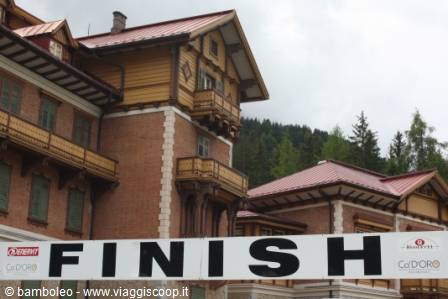 Finish banner in front of large wooden and brick building with mountain