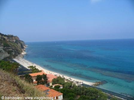 Turquoise sea beneath orange rooftops along a white rocky shoreline
