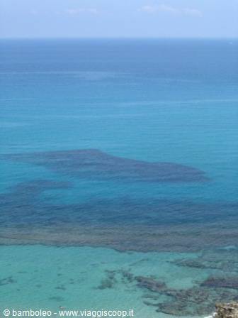 turquoise sea with rocks emerging beneath a blue sky